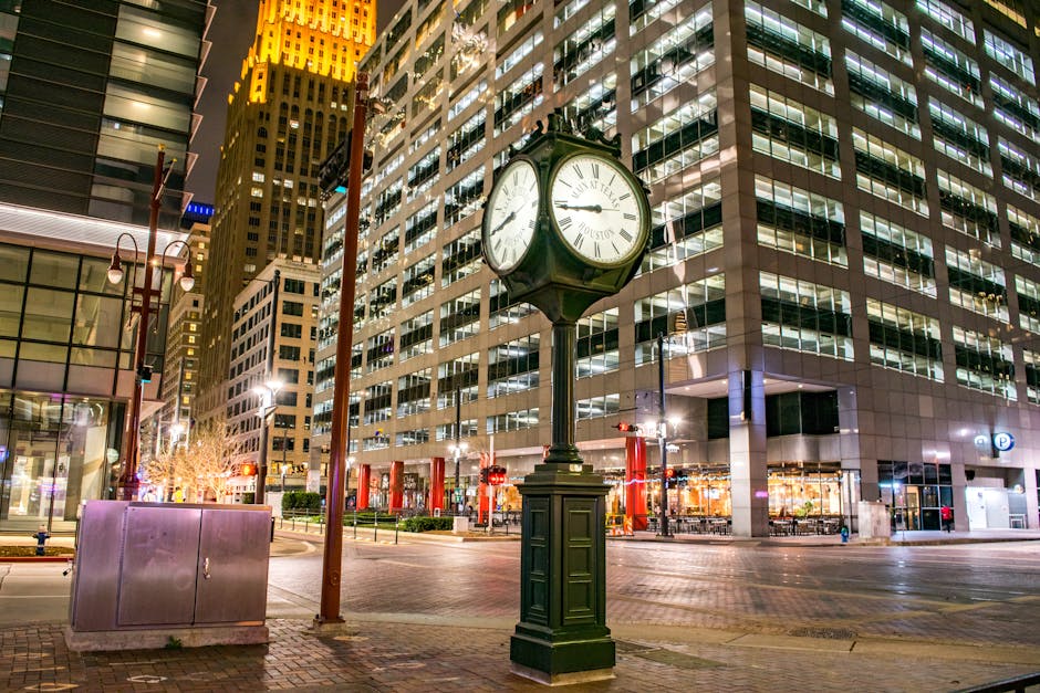 Illuminated clock and modern skyscrapers in downtown Houston at night.